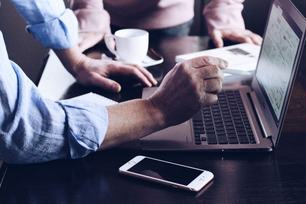 outsourced IT support for business, a hand pointing towards a laptop screen